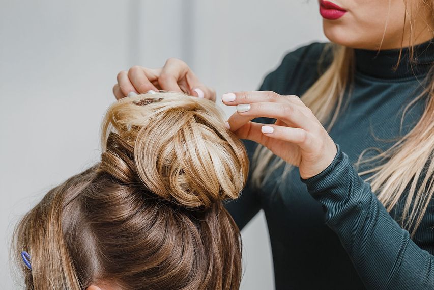 Eine Frau mit blonden Haaren bekommt ihre Haare nach oben gesteckt